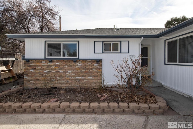 view of side of home with a shingled roof and fence