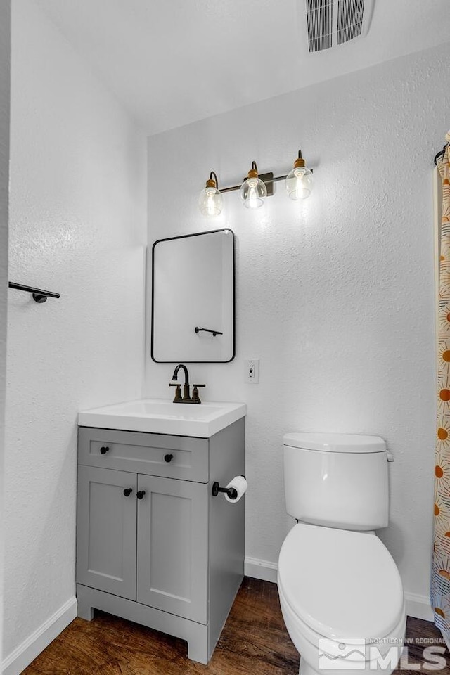 bathroom featuring toilet, baseboards, visible vents, and wood finished floors