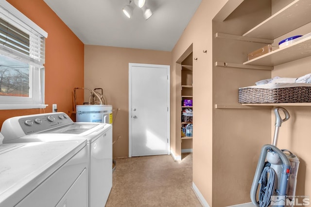 clothes washing area with washing machine and dryer, laundry area, electric water heater, and baseboards