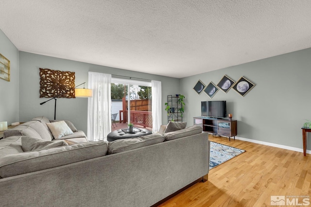 living area featuring a textured ceiling, wood finished floors, and baseboards