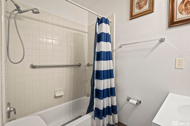 bathroom featuring a textured wall, vanity, and shower / bathtub combination with curtain
