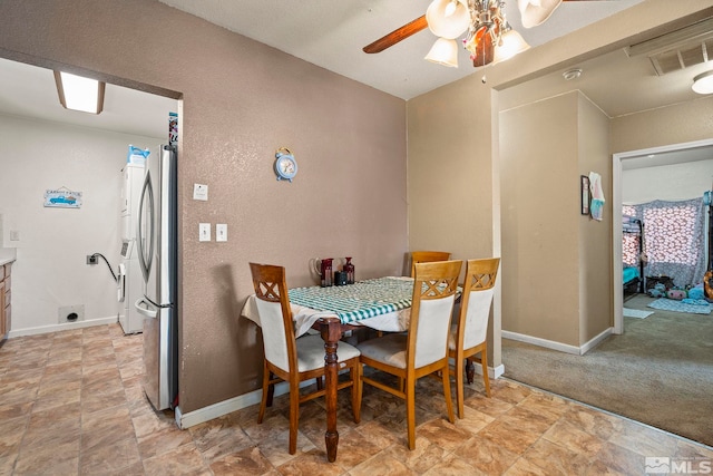 dining room with a textured wall, visible vents, ceiling fan, and baseboards
