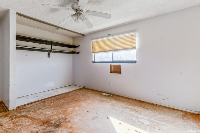 empty room with ceiling fan and a textured ceiling