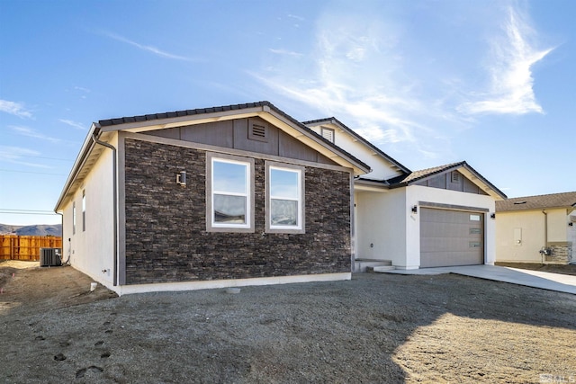 ranch-style house with cooling unit, a garage, fence, stone siding, and concrete driveway