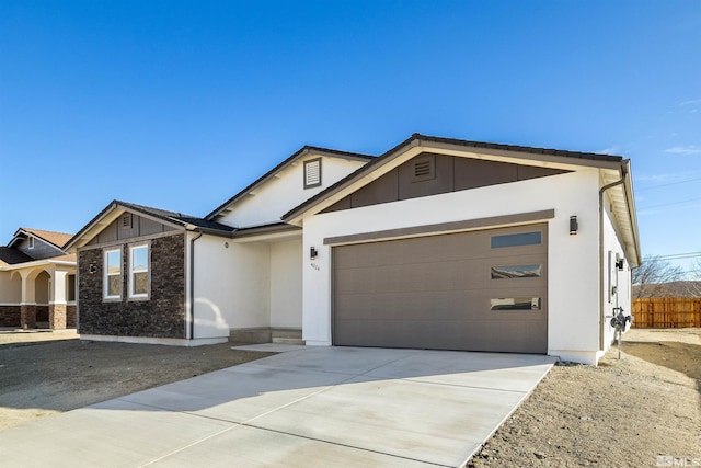 view of front facade featuring a garage, stone siding, driveway, and stucco siding