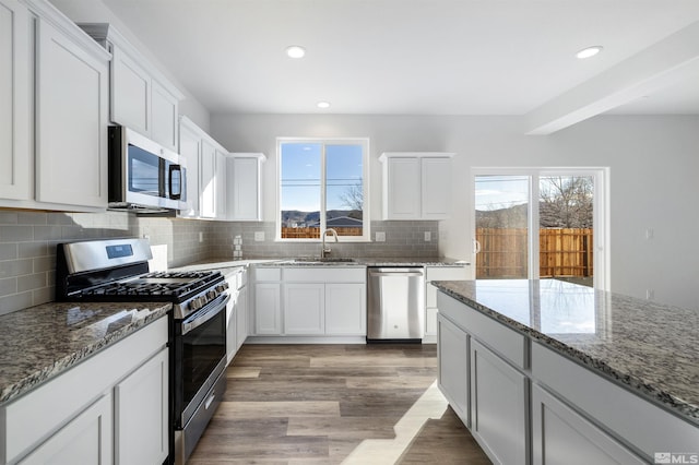 kitchen featuring stainless steel appliances, light wood-style floors, white cabinetry, and a sink