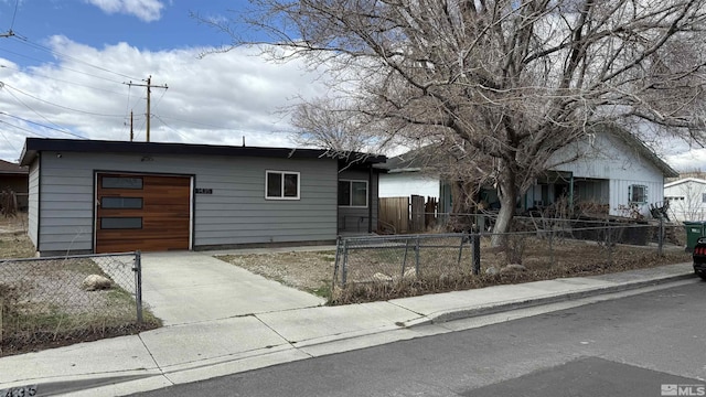 ranch-style home featuring a fenced front yard, concrete driveway, and an attached garage