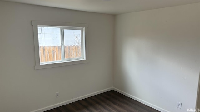 empty room with dark wood finished floors and baseboards