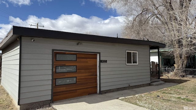 view of outdoor structure with a garage and fence