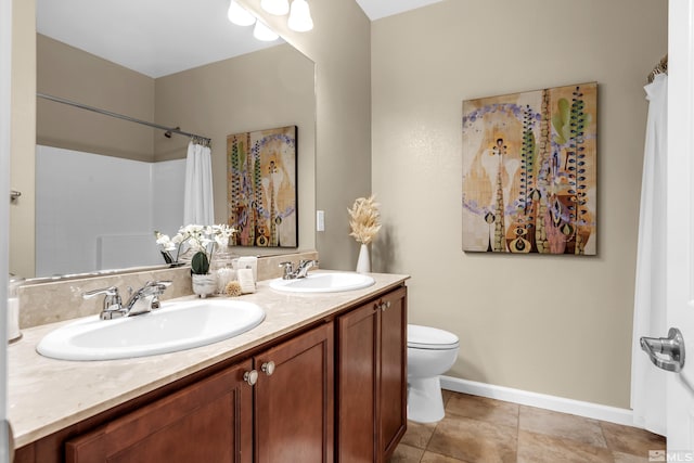 bathroom featuring double vanity, a sink, toilet, and baseboards