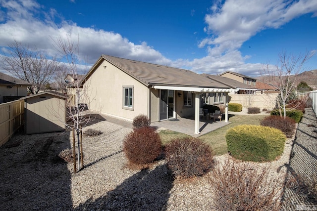 back of property with a patio, stucco siding, a storage shed, a fenced backyard, and an outdoor structure