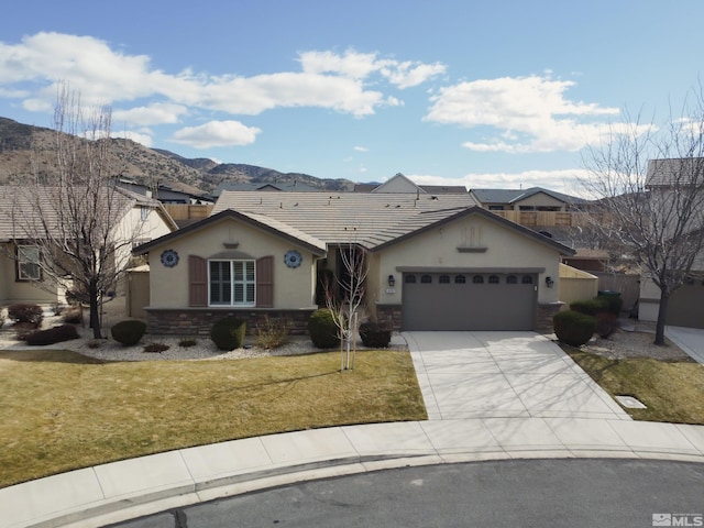 view of front of property with stucco siding, an attached garage, a front yard, a mountain view, and stone siding