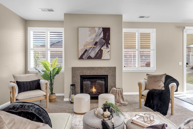 sitting room with carpet floors, a glass covered fireplace, visible vents, and baseboards