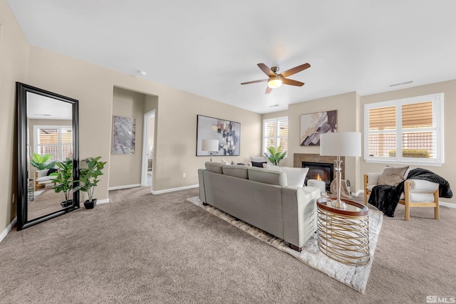 living room with carpet, visible vents, baseboards, and a glass covered fireplace