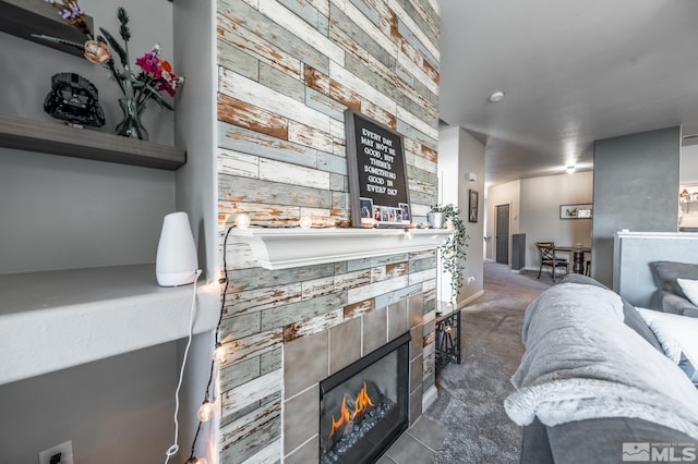 carpeted living room with an accent wall, a fireplace, and wooden walls