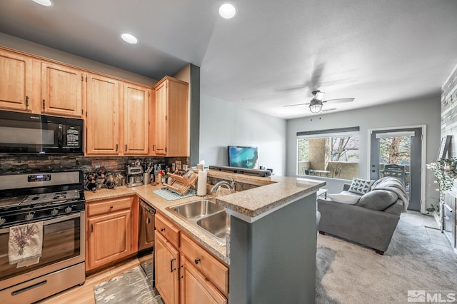 kitchen with decorative backsplash, open floor plan, black appliances, light brown cabinets, and a sink