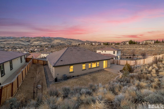 rear view of house featuring stucco siding, central AC, a mountain view, a fenced backyard, and a tiled roof