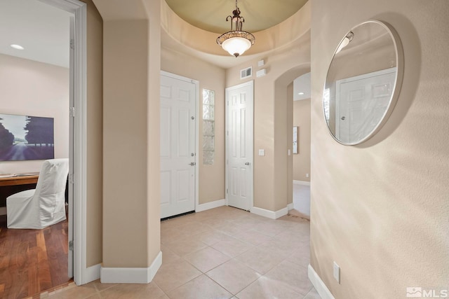 foyer entrance with light tile patterned floors, baseboards, and visible vents