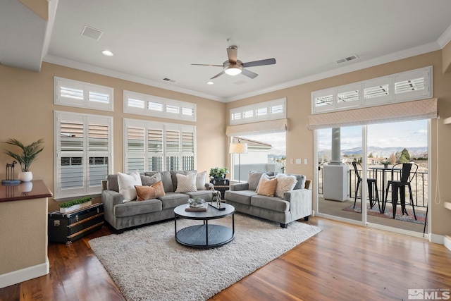 living room featuring a ceiling fan, visible vents, crown molding, and wood finished floors