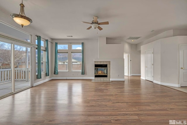 unfurnished living room featuring baseboards, visible vents, a tiled fireplace, and wood finished floors