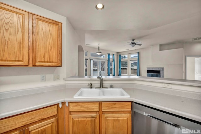 kitchen with a sink, ceiling fan, light countertops, and stainless steel dishwasher