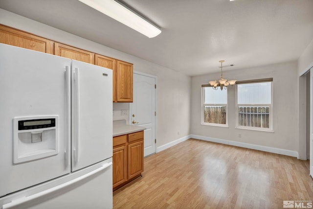 kitchen with a notable chandelier, white fridge with ice dispenser, light countertops, and light wood-style floors