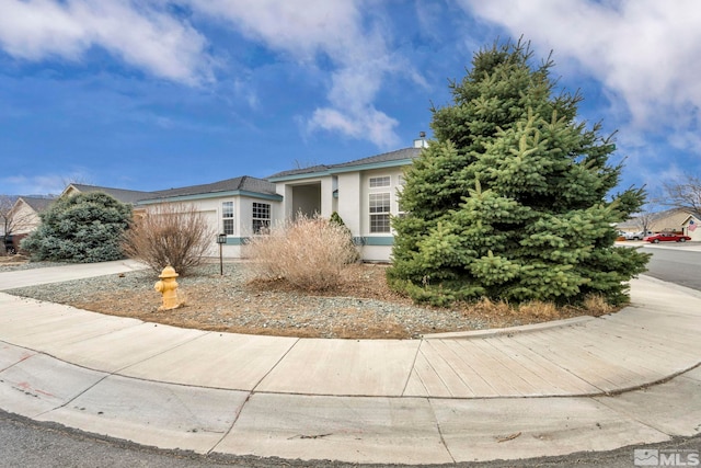 view of front of property featuring a garage, concrete driveway, and stucco siding