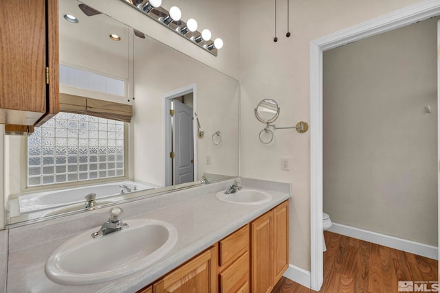 full bathroom with baseboards, a sink, toilet, and wood finished floors