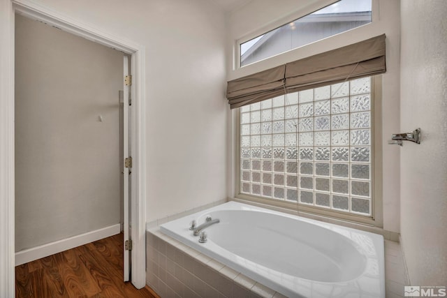 full bathroom with a garden tub, baseboards, and wood finished floors