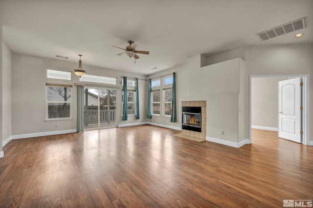 unfurnished living room featuring baseboards, a fireplace, visible vents, and wood finished floors