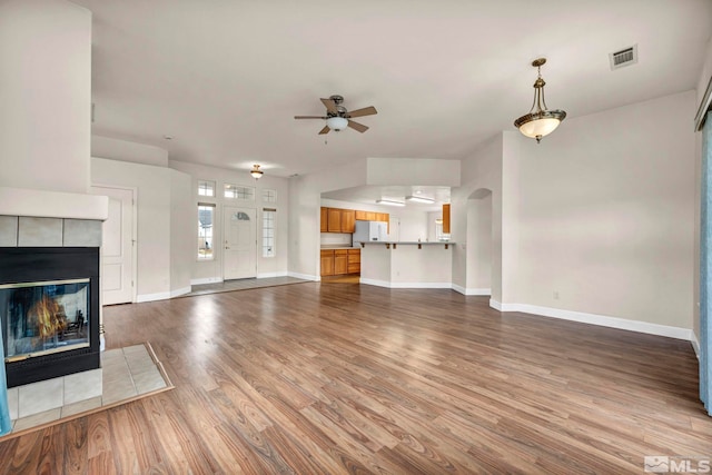 unfurnished living room featuring a fireplace, wood finished floors, visible vents, and baseboards