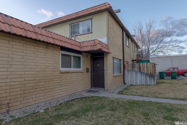 view of front of house with a front yard, fence, and a tiled roof