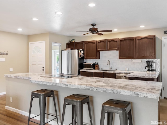 kitchen with tasteful backsplash, a kitchen breakfast bar, a sink, and freestanding refrigerator