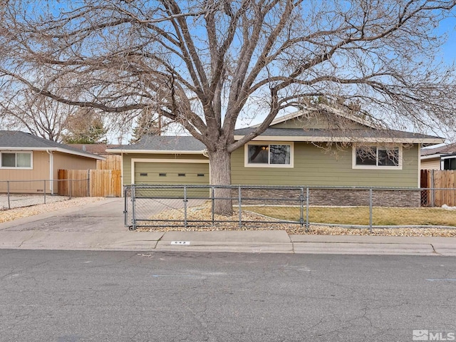 ranch-style home with a fenced front yard, concrete driveway, and a garage