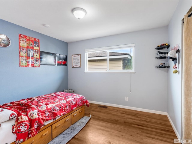 bedroom featuring wood finished floors, visible vents, and baseboards