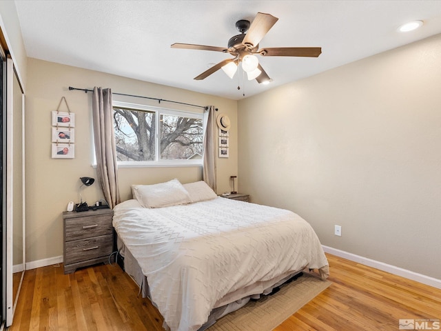 bedroom featuring ceiling fan, a closet, wood finished floors, and baseboards