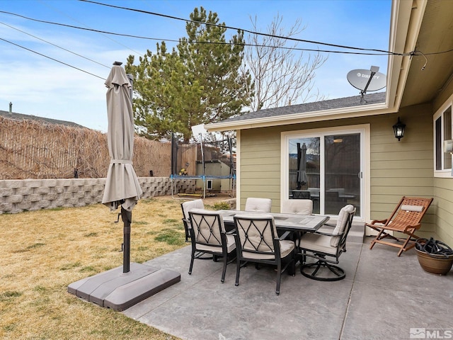 view of patio / terrace with outdoor dining space, a trampoline, and fence