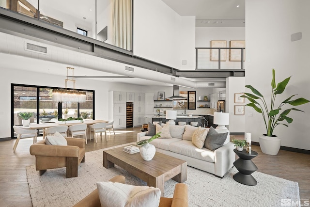 living area with light wood-type flooring, a towering ceiling, and visible vents