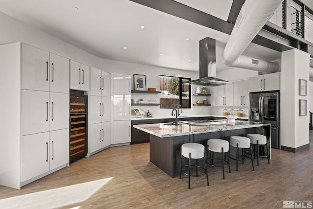 kitchen with open shelves, light wood finished floors, stainless steel fridge, and island exhaust hood