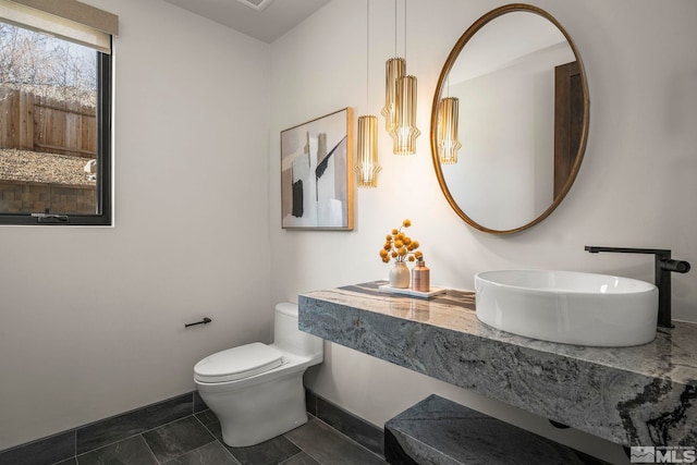 bathroom with toilet, tile patterned flooring, baseboards, and a sink