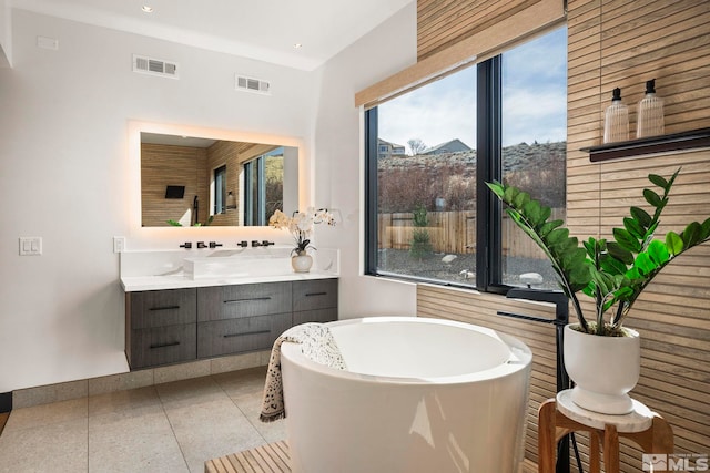 bathroom featuring tile patterned flooring, a freestanding tub, visible vents, and vanity