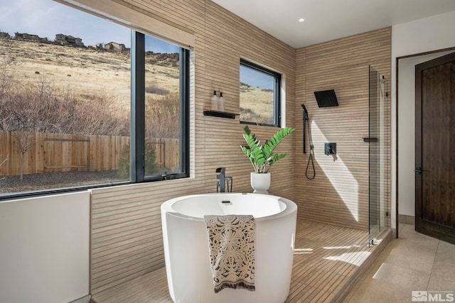 bathroom with tile patterned flooring, a freestanding bath, and a shower stall