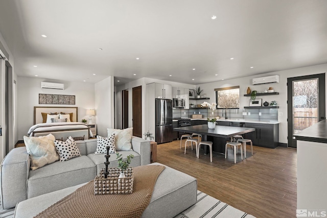 living area featuring light wood finished floors, plenty of natural light, and a wall mounted AC