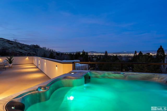 pool at dusk with a jacuzzi and a mountain view