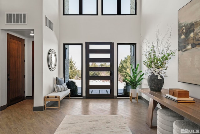 entrance foyer featuring a high ceiling, visible vents, and wood finished floors