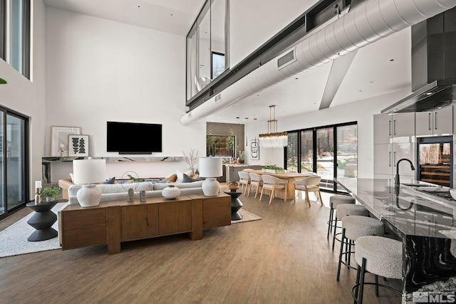 living area with visible vents, a towering ceiling, and wood finished floors