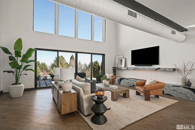 living room featuring visible vents, wood finished floors, and a towering ceiling