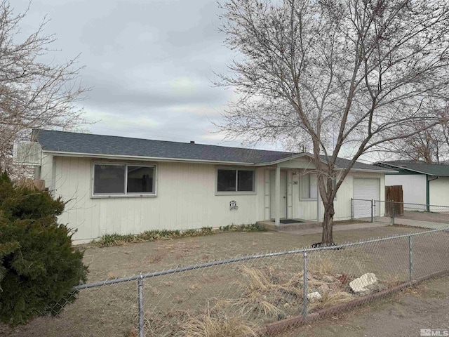 ranch-style home with a garage, fence private yard, and roof with shingles