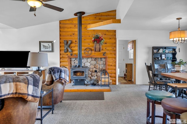 living area with ceiling fan, carpet flooring, vaulted ceiling, log walls, and a wood stove