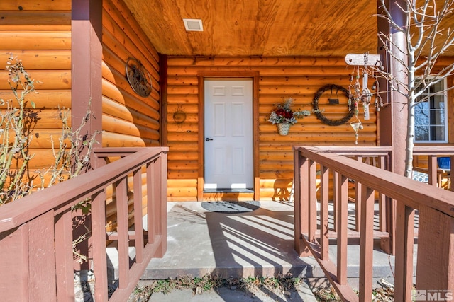 property entrance featuring log veneer siding and visible vents